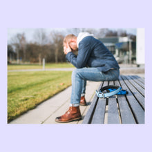 Load image into Gallery viewer, Man sitting on a bench with his head in his hands. A blue dog collar is sitting on the bench next to him.