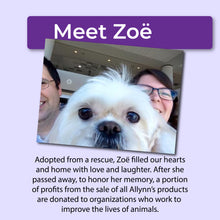 Load image into Gallery viewer, White dog being held by two people with a purple banner above that reads, "Meet Zoë" and text below that reads, "Adopted from a rescue, Zoë filled our hearts and home with love and laughter. After she passed away, to honor her memory, a portion of profits from the sale of all Allynn's products are donated to organizations who work to improve the lives of animals."
